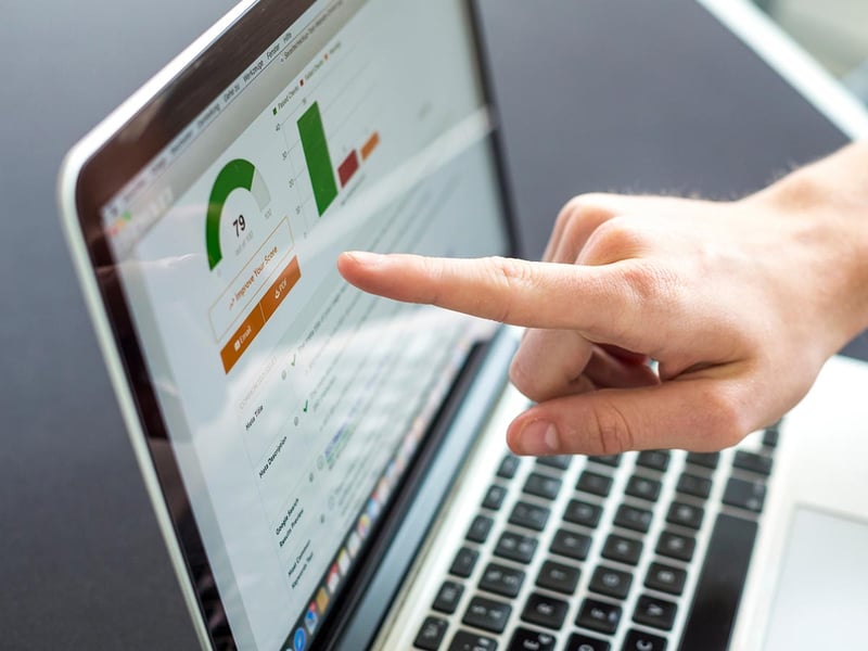 Closeup of laptop screen with a hand pointing at a statistic