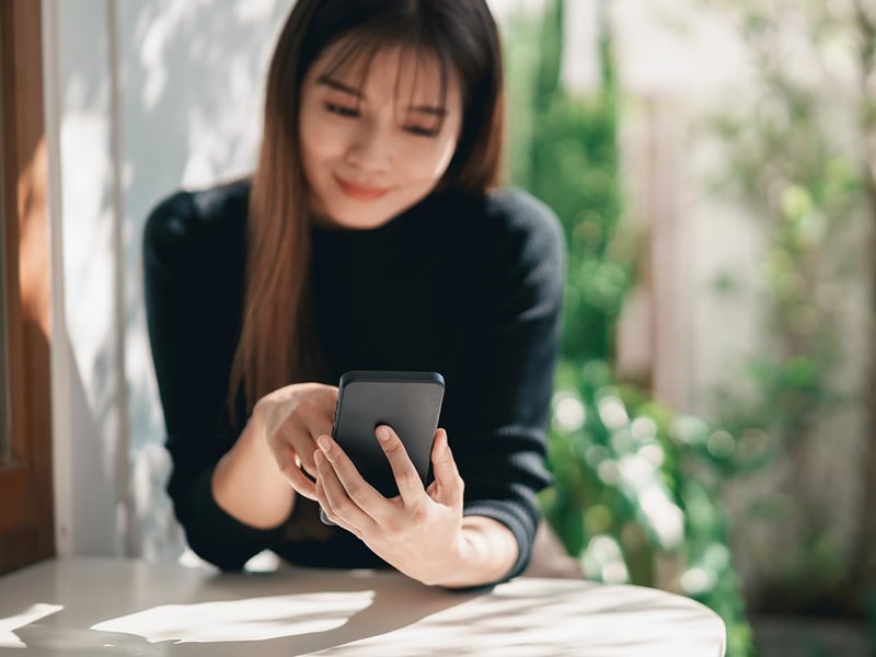 Smiling young woman holding a cellphone