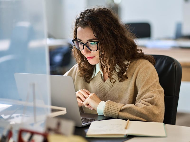 Young professional businesswoman wearing glasses using a laptop