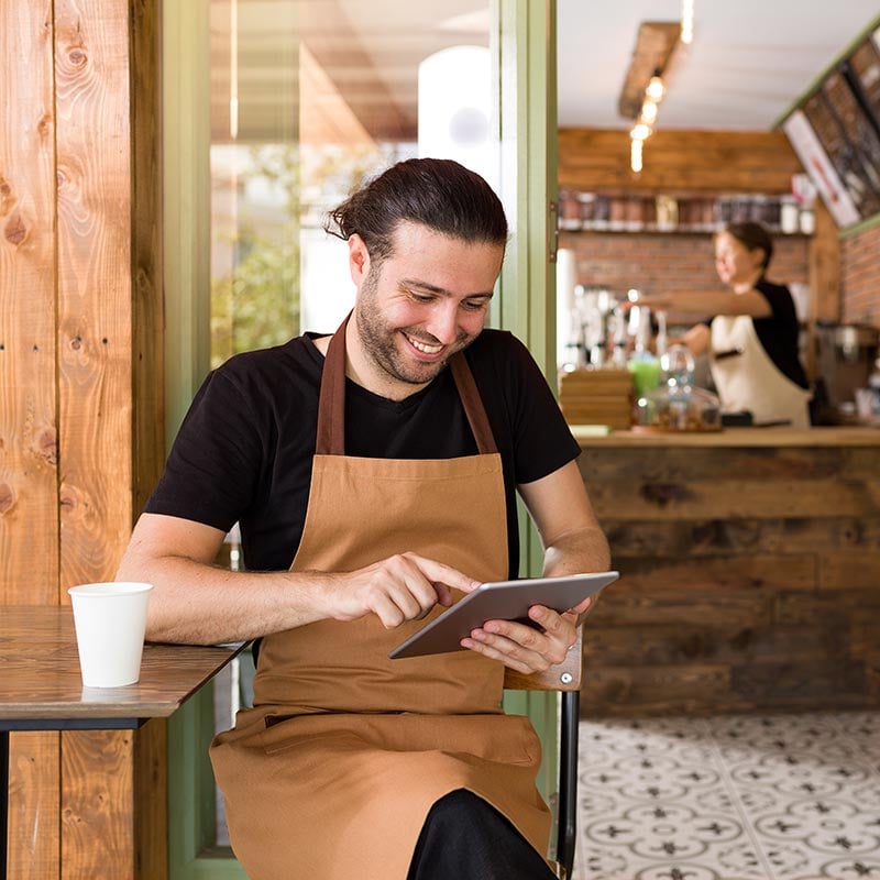 Man sitting in a coffee shop looking at a tablet