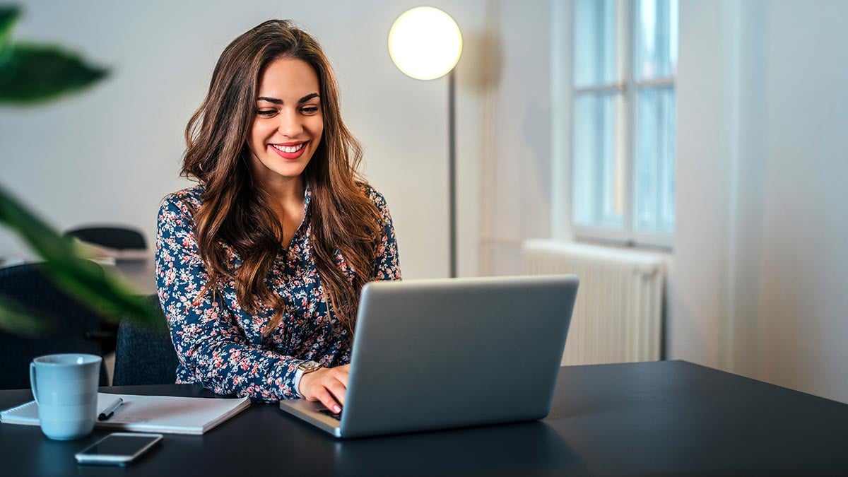 Cheerful woman using laptop at workplace Cheerful woman using laptop at workplace
