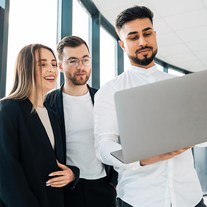 Two men and a woman looking at a laptop, discussing the company's growth rate