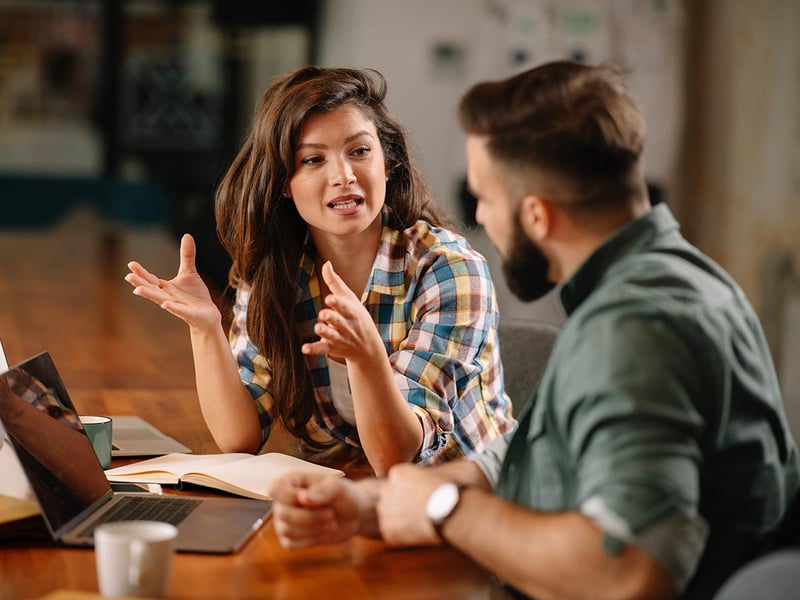 A man and woman working together at a table with laptops