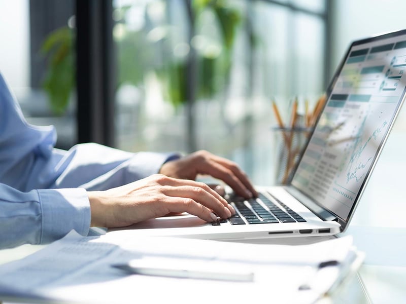Closeup of hands on a laptop that's displaying financial data 
